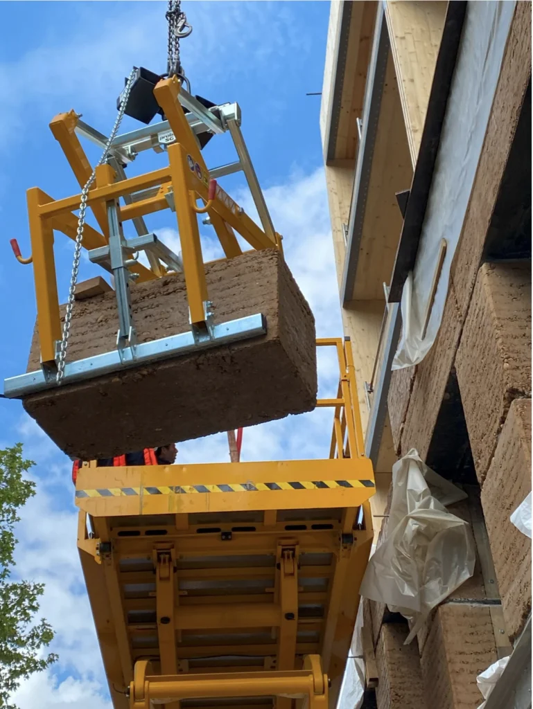 Bloc de pisé préfabriqué en terre crue dans une grue - Chantier façade de Boulogne Billancourt